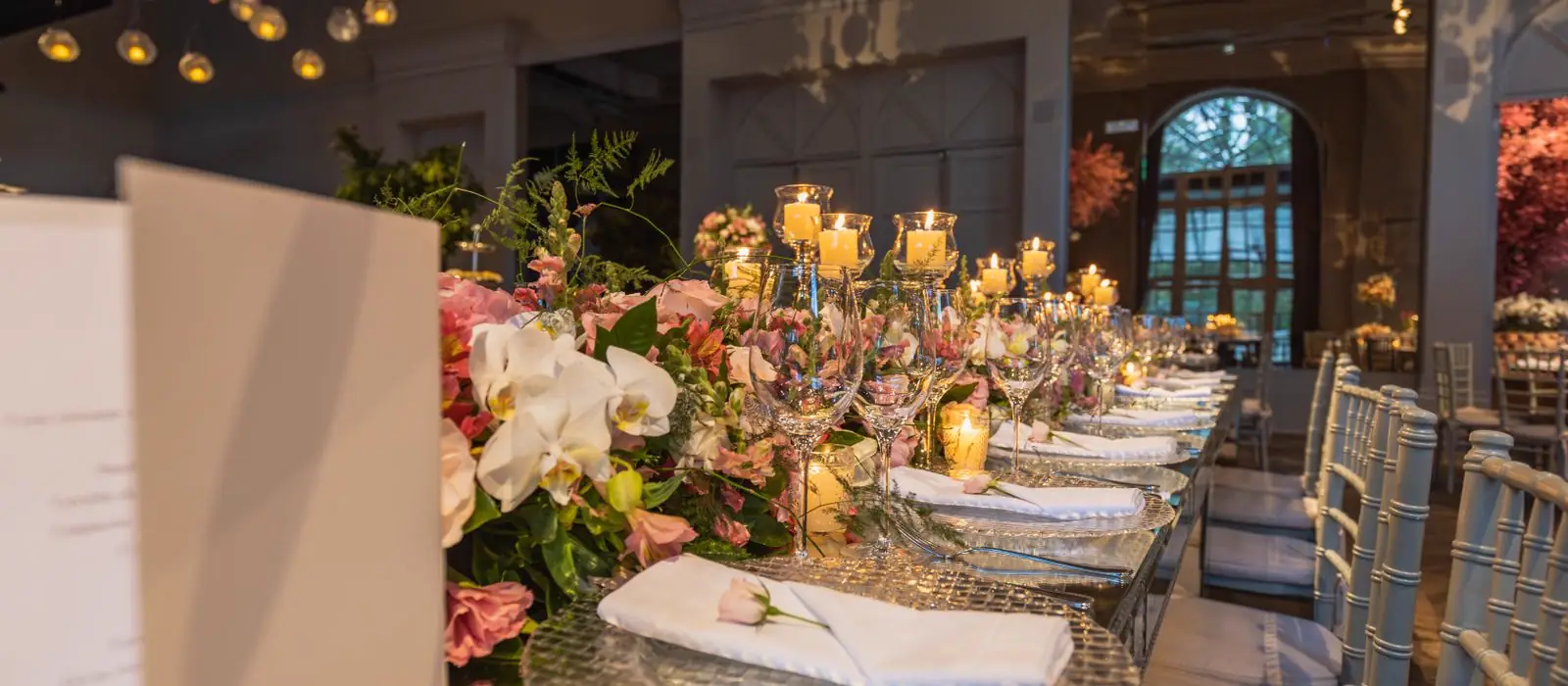 Sală de eveniment decorată cu aranjamente florale și lumânări